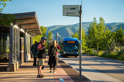 Passengers standing at a bus station with a bus approaching.